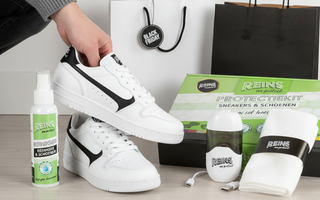 Zwarte vrijetijdssneakers met onderhoudsproducten en Black Friday tasje op de achtergrond.